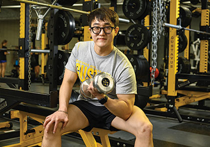 Student lifting weights in gym. Links to Beneficiary Designations